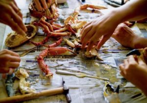 Multiple people grabbing lobster legs and opening them.