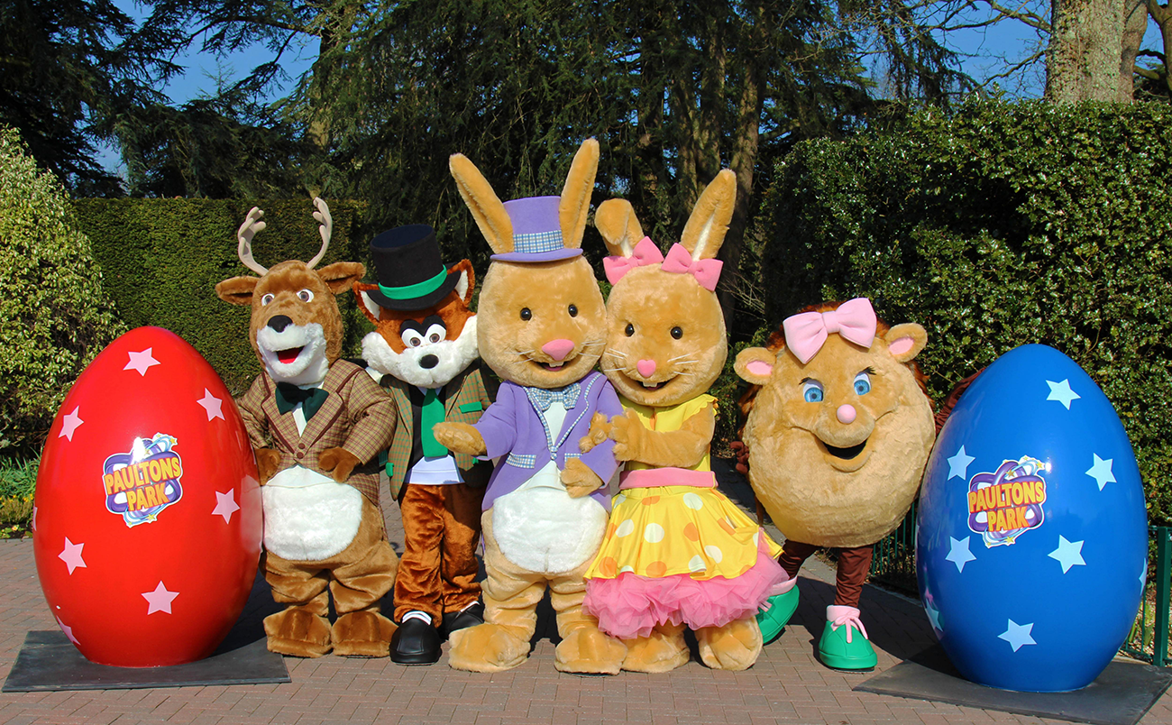 Five animal character costumes standing next to two eggs with the Paultons Park logo on it.