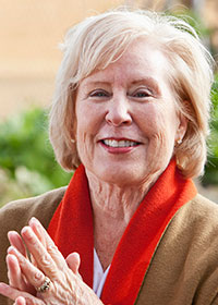 An older woman smiles at the camera.