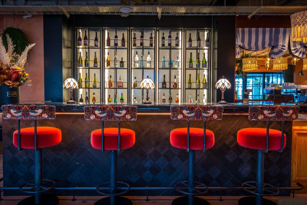 Four barstools providing seating for a bar top with a wall of liquor behind.